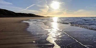 a beach with the sun shining on the water at The Wayside and Whisky Barn in Whitbeck