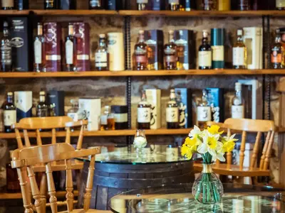 a table with two chairs and a vase with yellow flowers at The Wayside and Whisky Barn in Whitbeck