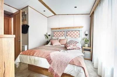 a bedroom with a large bed with pink pillows at Platinum Holiday Caravan in Bothel