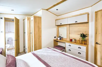a bedroom with a bed and a desk and a sink at Platinum Holiday Caravan in Bothel