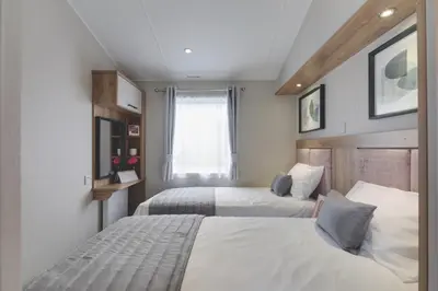 a bedroom with two beds and a window at Platinum Holiday Caravan in Bothel