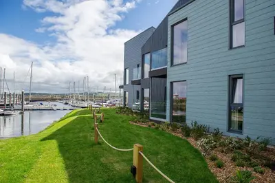 a building with a grassy yard next to a marina at The Salt Lodge in Troon