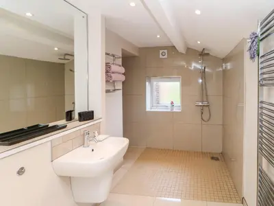 a white bathroom with a sink and a shower at Berrymoor Cottage in Brampton
