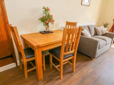 a wooden dining room table with chairs and a couch at Tilberthwaite Farm Cottage in Coniston
