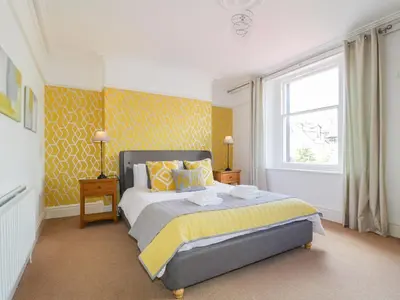 a bedroom with a bed with yellow walls and a window at Sefton House in Keswick