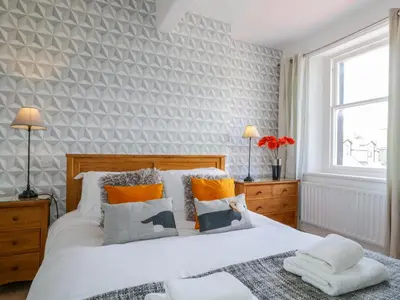 a bedroom with a white bed with orange and gray pillows at Sefton House in Keswick