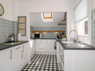 a kitchen with white cabinets and a checkered floor at Sefton House in Keswick