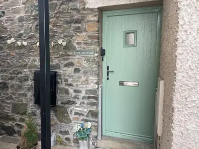 a door to a stone building with a green door at Tithe Cottage in Keswick