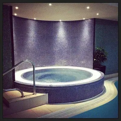 a bathroom with a jacuzzi tub with blue tiles at Tithe Cottage in Keswick