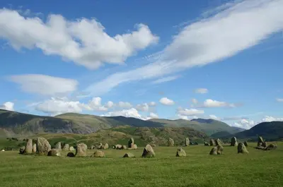 a field with rocks in a field with mountains at Tithe Cottage in Keswick