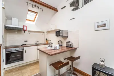a kitchen with white walls and a wooden counter top at Tithe Cottage in Keswick