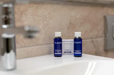 two bottles of blue liquid sitting on a bathroom sink at Iona Residence - Donnini Apartments in Ayr