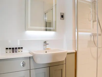 a white bathroom with a sink and a shower at Cottam Road in Threlkeld