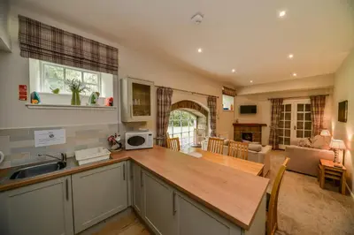 a kitchen with a counter top and a living room at Blairquhan Cottages in Maybole