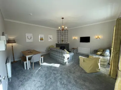 a living room with a couch a table and a tv at Blairquhan Cottages in Maybole