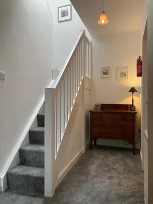 a staircase in a home with a wooden dresser at Providence Cottage in Kirkcudbright