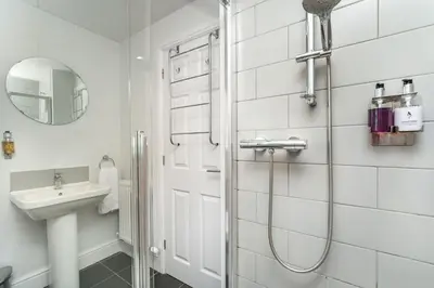 a white bathroom with a shower and a sink at 5 The Townhouse in Keswick