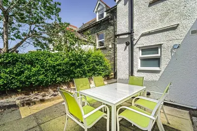 a white table and four green chairs on a patio at 5 The Townhouse in Keswick