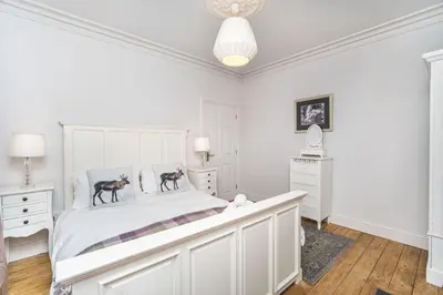 a white bedroom with a large white bed with two deer statues on it at 5 The Townhouse in Keswick