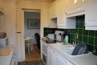 a kitchen with white cabinets and green tiles at 31 Laigh Isle in Isle of Whithorn