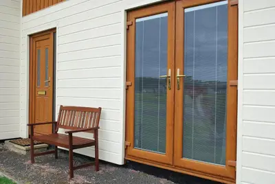 a wooden door with a bench next to a house at 31 Laigh Isle in Isle of Whithorn