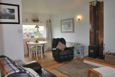 a living room with a couch and a chair and a stove at 31 Laigh Isle in Isle of Whithorn