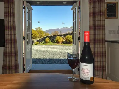 a bottle of wine sitting on a table with a glass at Field House Bothy - Uk12571 in Borrowdale Valley