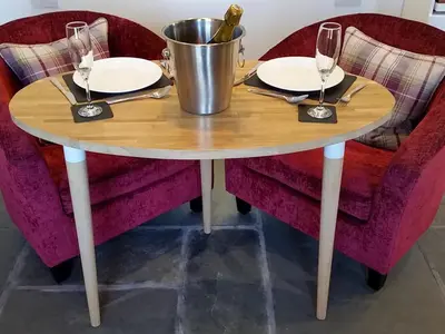 a wooden table with two chairs and a bucket of wine glasses at Field House Bothy - Uk12571 in Borrowdale Valley