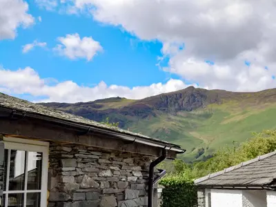a stone house with mountains in the background at Field House Bothy - Uk12571 in Borrowdale Valley