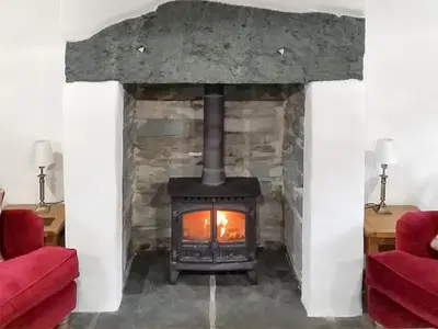 a stone fireplace with a stove in a room at Field House Cottage - Uk12573 in Borrowdale Valley