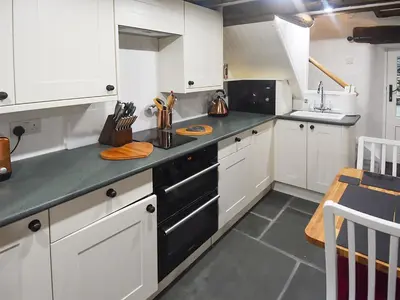 a kitchen with white cabinets and a black stove at Field House Cottage - Uk12573 in Borrowdale Valley