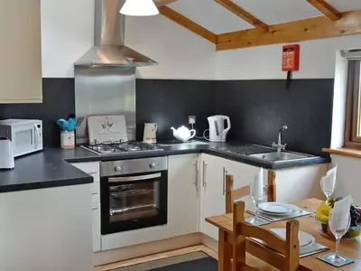 a kitchen with a stove top oven next to a table at Pheasant Cottage - Ukc3428 in Dalston