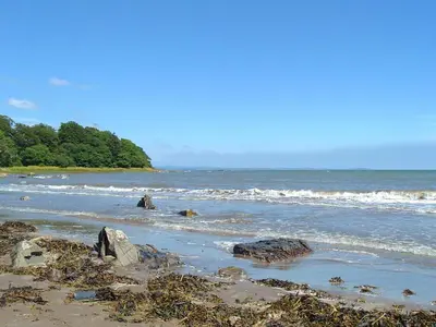 a beach with some rocks and the ocean at Orchard Cottage - Uk12525 in Garlieston