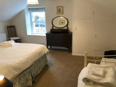 a bedroom with a bed and a mirror and a dresser at Laundry Cottage in Dumfries
