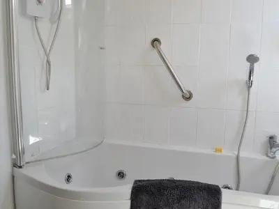 a bathroom with a tub and a shower with a towel at Curlew Cottage in Creetown