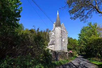 an old stone church with a steeple on a road at Tower Lodge in Auchencairn