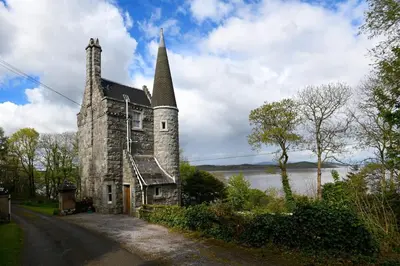 an old stone church with a steeple on the side of a road at Tower Lodge in Auchencairn