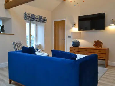 a blue couch in a living room with a tv at The Hayloft in Caldbeck