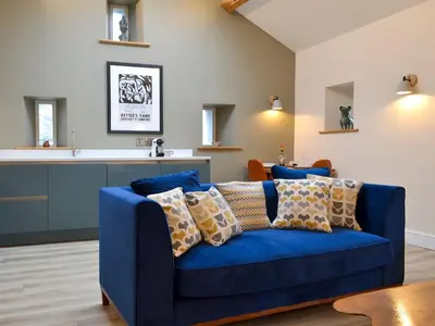 a blue couch in a living room with a kitchen at The Hayloft in Caldbeck