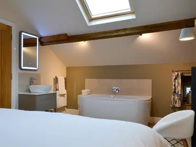 a bathroom with a large tub and a sink at The Hayloft in Caldbeck