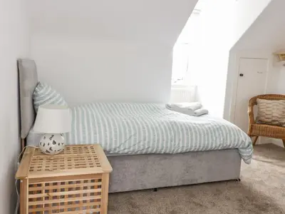 a bedroom with a bed and a table with a lamp at Daisy Cottage in Moffat