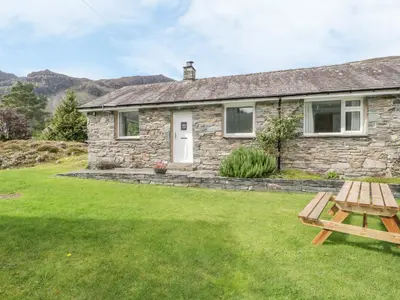 a stone cottage with a picnic table in the yard at Rock Cottage in Keswick