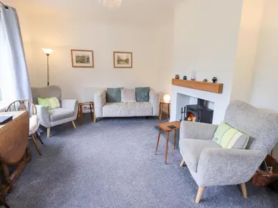 a living room with chairs and a fireplace at Rock Cottage in Keswick