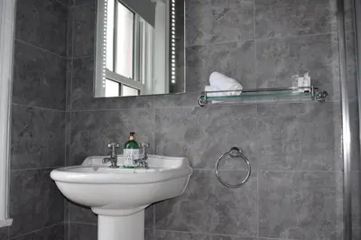 a bathroom with a sink and a mirror at Woodlyn Guest House in Gatehouse of Fleet