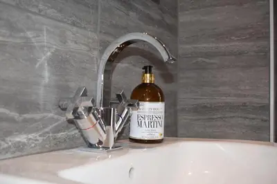 a bottle of whiskey sitting on a sink in a bathroom at Woodlyn Guest House in Gatehouse of Fleet