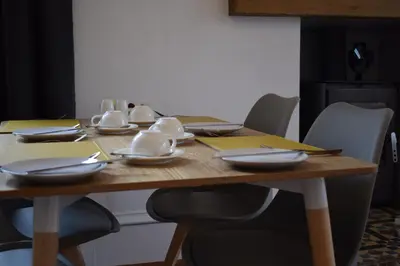a wooden table with plates and utensils on it at Woodlyn Guest House in Gatehouse of Fleet