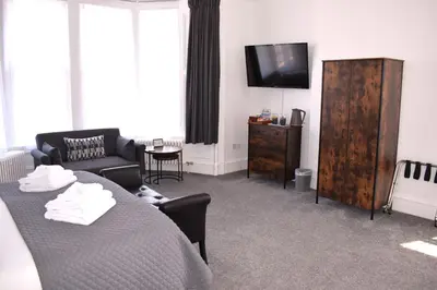 a living room with a bed and a tv at Woodlyn Guest House in Gatehouse of Fleet