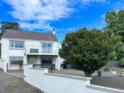 a white house with a tree in front of it at Stinchar View in Ballantrae