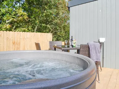 a large hot tub on a patio with a table at Lapwing in Westward
