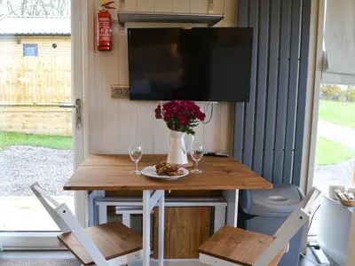 a table with two chairs and a television on a porch at Merlin's Cabin in Westward